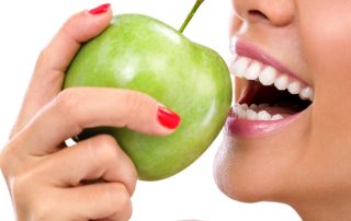 Woman with dental implant eating an apple
